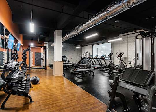 a gym with cardio machines and weights on a wooden floor at Textile Apartments, Cincinnati, Ohio