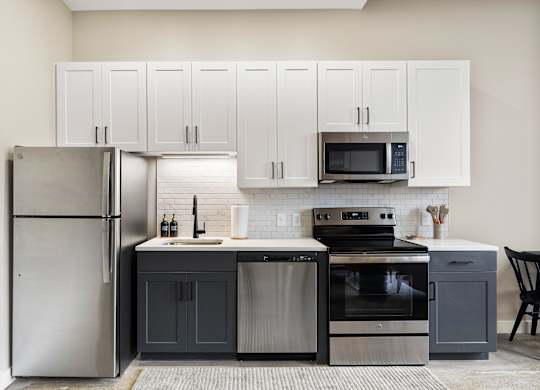 a kitchen with stainless steel appliances and white cabinets at Textile Apartments, Cincinnati, OH