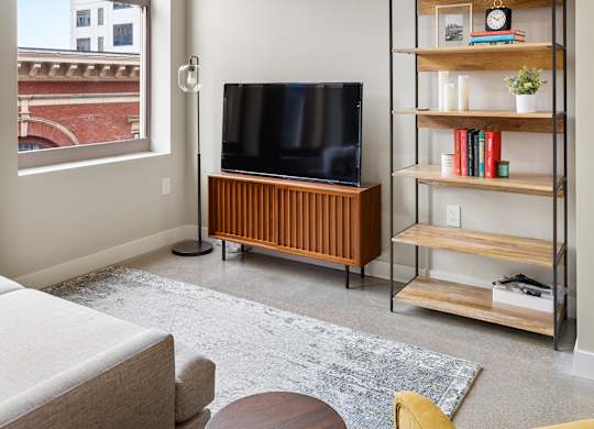 a living room with a couch and a television and a bookshelf at Textile Apartments, Cincinnati