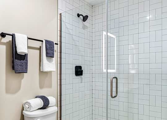 a white bathroom with a toilet and a shower at Textile Apartments, Ohio