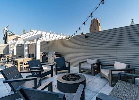 a roof top patio with chairs and tables and a fire pit at Textile Apartments, Ohio