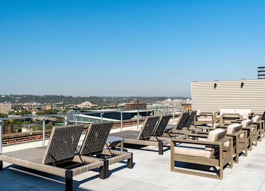 a row of lounge chairs on a roof top overlooking a city at Textile Apartments, Cincinnati