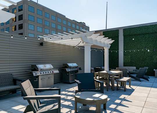 a patio with tables and chairs and a barbecue grill on a roof at Textile Apartments, Ohio, 45202
