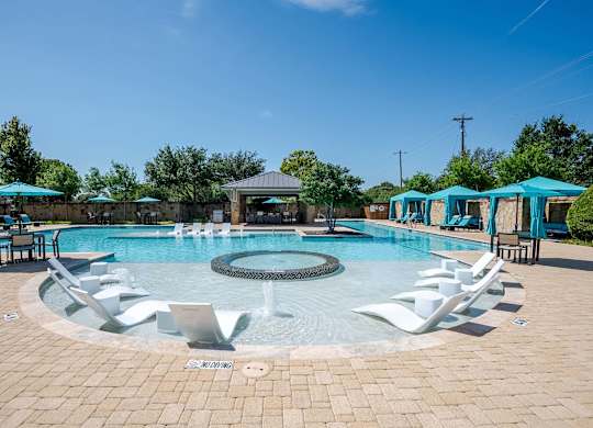 a resort style pool with white chairs and blue umbrellas at Discovery at Craig Ranch, McKinney