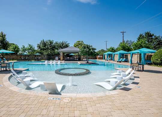 a resort style swimming pool with lounge chairs and umbrellas at Discovery at Craig Ranch, Texas