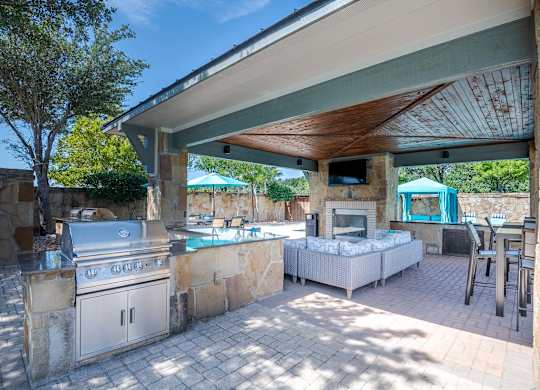 a covered outdoor kitchen with a grill and a pool at Discovery at Craig Ranch, McKinney, TX