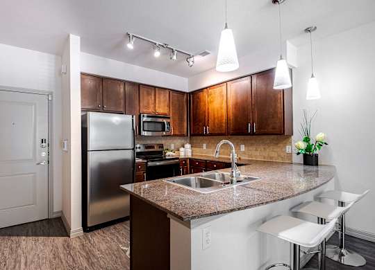 a kitchen with a granite counter top and a stainless steel refrigerator at Discovery at Craig Ranch, McKinney, TX