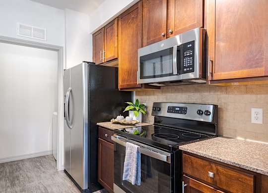 a kitchen with stainless steel appliances and wooden cabinets at Discovery at Craig Ranch, McKinney, TX