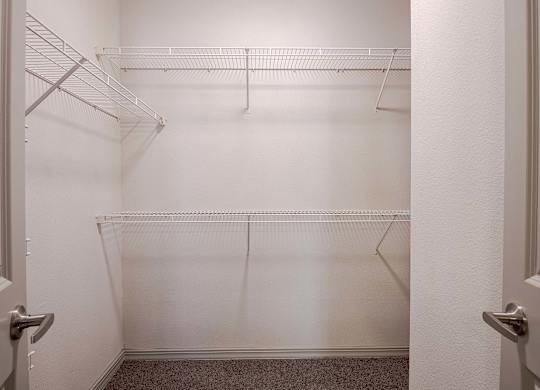 a walk in closet with empty shelves in a white room at Discovery at Craig Ranch, McKinney, Texas