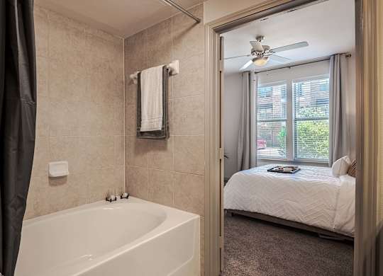 a bathroom with a tub and a bedroom with a bed at Discovery at Craig Ranch, Texas