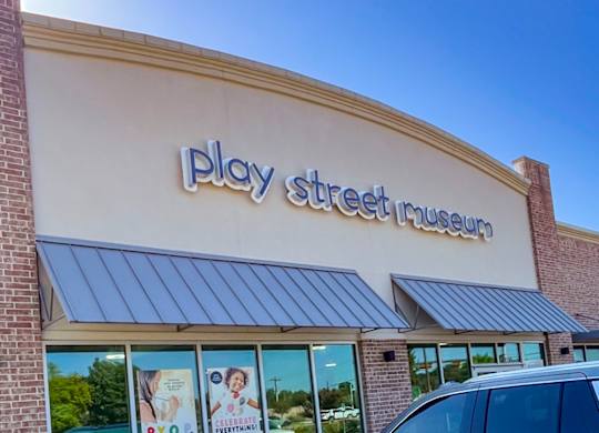 A Play Street Museum storefront with a blue sky in the background at Craig Ranch, McKinney, TX.