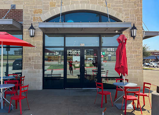 Sweetwaters Coffee & Tea storefront with red umbrellas and chairs at Discovery at Craig Ranch, McKinney, 75070.