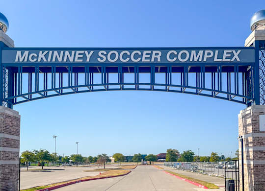 McKinney Soccer Complex entrance with a blue arch and red brick pillars at Craig Ranch, McKinney, TX