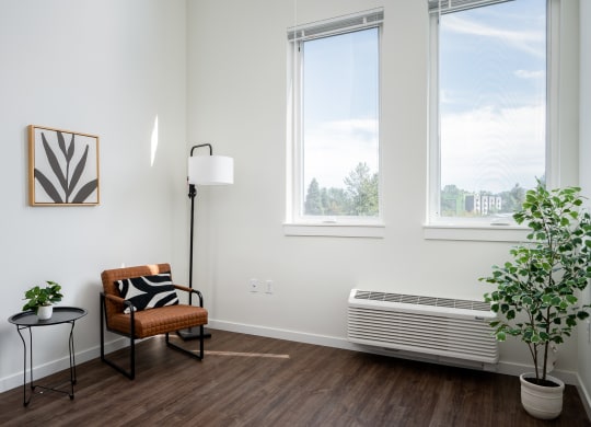 a living room with a chair and large windows for natural light