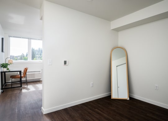 a room with white walls and a mirror in the corner