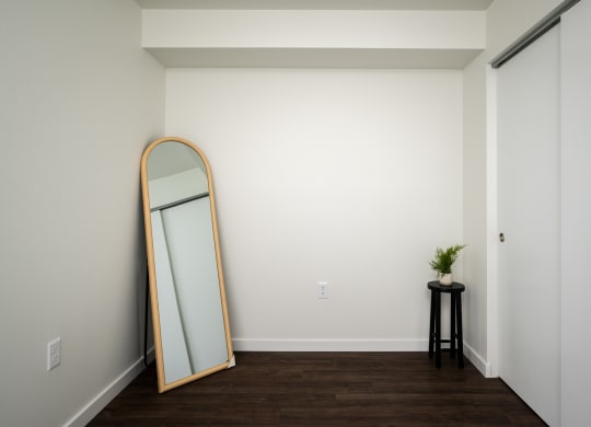a mirror on a wall in a room with wooden floors and white walls