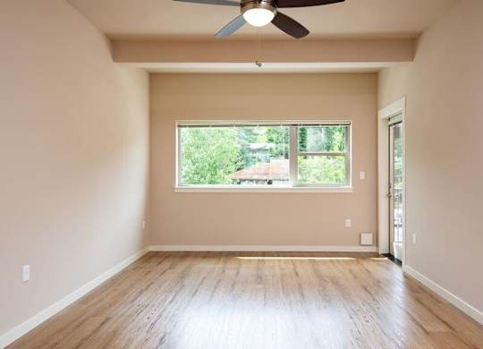 a empty living room with a window and a ceiling fan