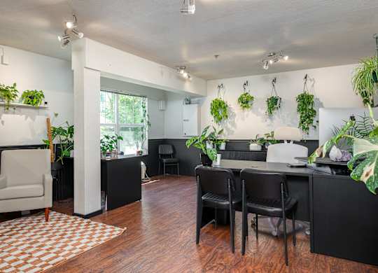 A room with a white chair and a table with a vase on it.