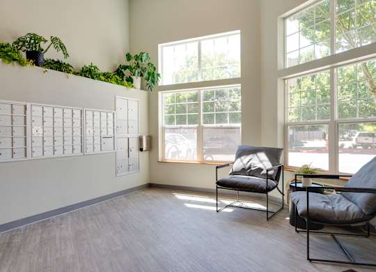 A room with a white wall, a window, and two chairs.