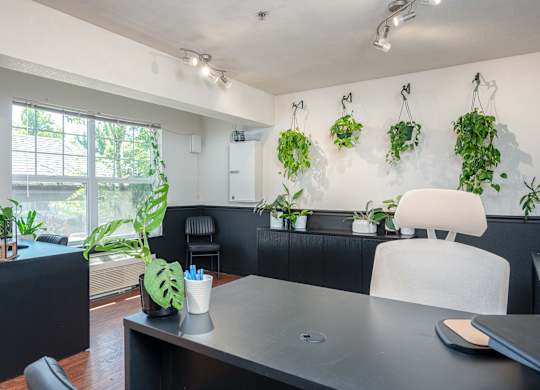 A black desk with a white chair and a potted plant on it.