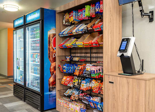 A vending machine selling snacks and drinks is next to a counter with a cash register.