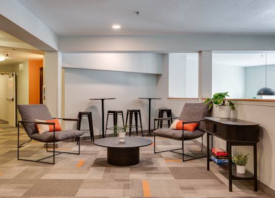 A modern lounge area with grey chairs and a round table.