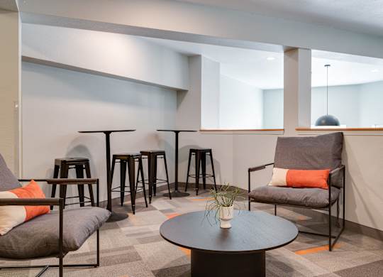 A modern living room with a grey sofa, a black coffee table, and a grey armchair.