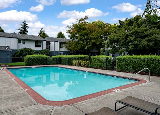 A small pool with a bench and a fence around it.