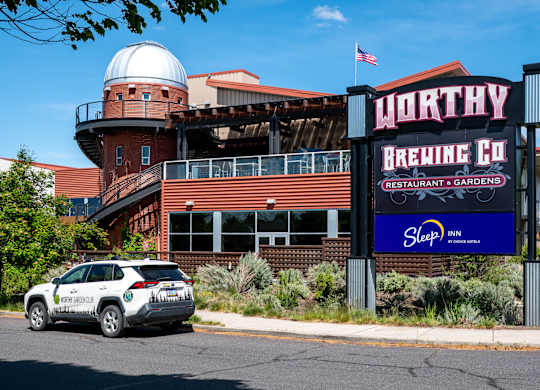 A car is parked in front of a building with a sign that says WORTHY BREWING CO.