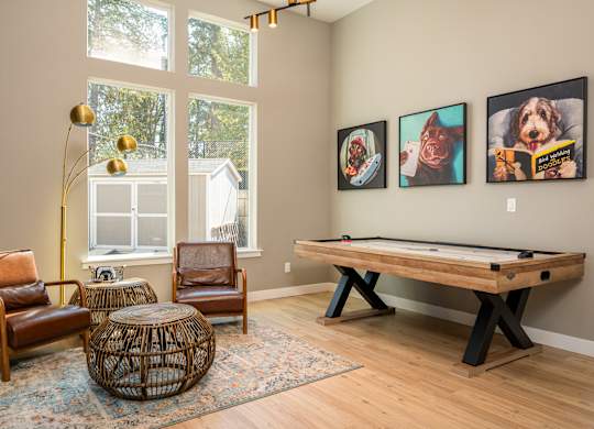 A room with a pool table and three framed pictures on the wall.