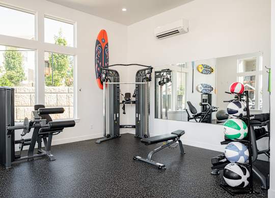 A gym with a variety of equipment including weights and a bench.