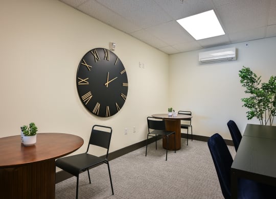 a room with a large clock on the wall and tables and chairs