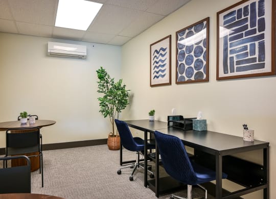 a conference room with a table and chairs and paintings on the wall
