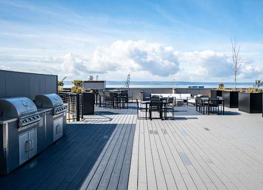 a rooftop patio with tables and chairs and a view of the ocean