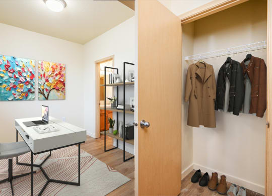 a closet with a white desk and a door to a closet