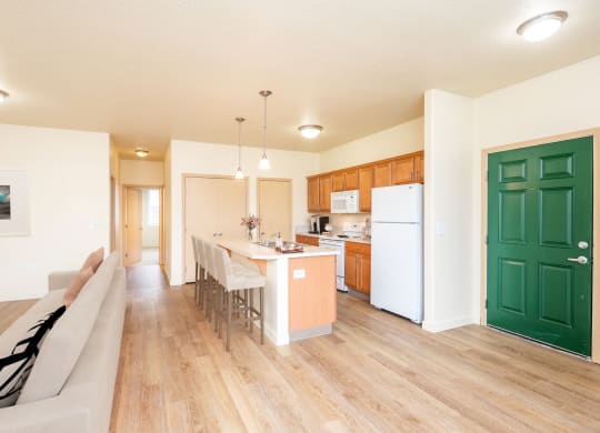 an open kitchen and living room with a dining table and a refrigerator