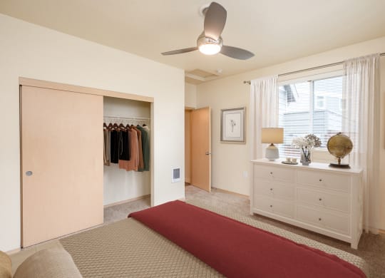 a bedroom with a bed and closet and a ceiling fan