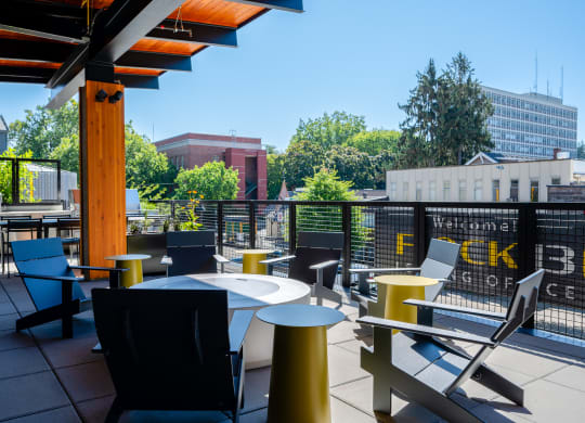a rooftop patio with tables and chairs and a building in the background