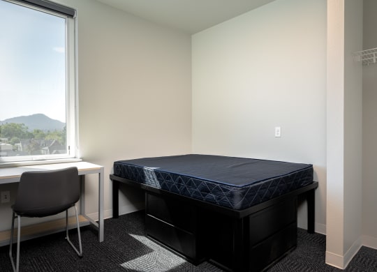 an empty bedroom with a bed and a desk and a window