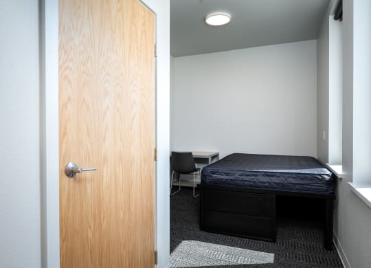 a bedroom with a bed and a door to a room with a desk