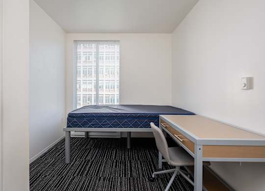 A bedroom with a bed, desk, and chair.