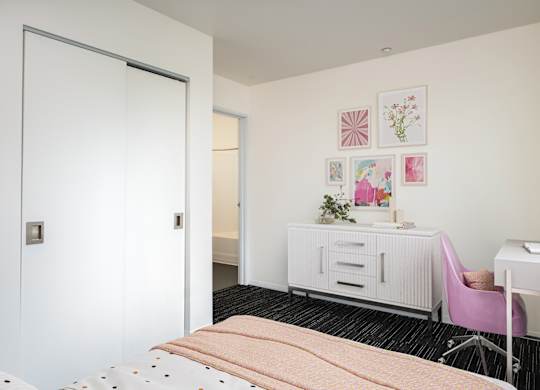 A bedroom with a bed, desk, and chair.