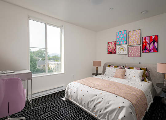 A bedroom with a large bed, a desk with a chair, and a window with a view of the outdoors.