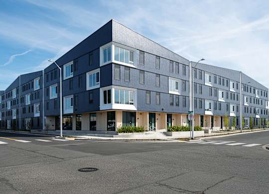 A modern multi-story building with a flat roof and large windows.