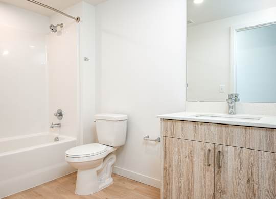A white toilet sits next to a bathtub in a bathroom.