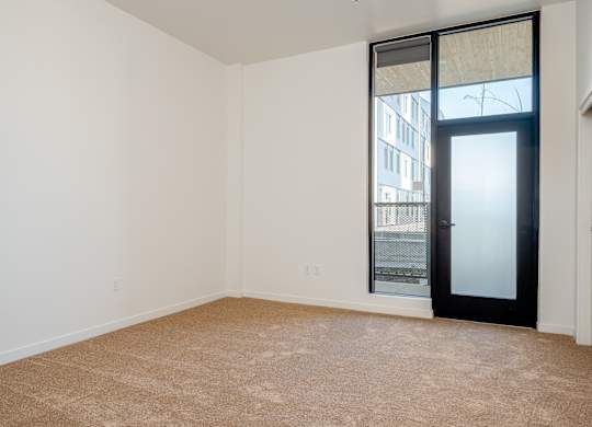 A room with a carpeted floor and a sliding glass door.
