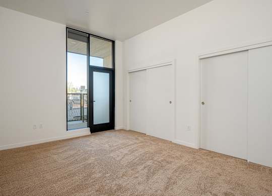 A room with a carpeted floor and a sliding glass door.