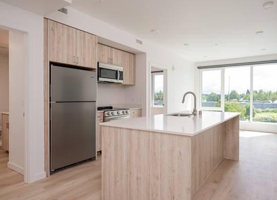 A kitchen with a refrigerator, microwave, and sink.