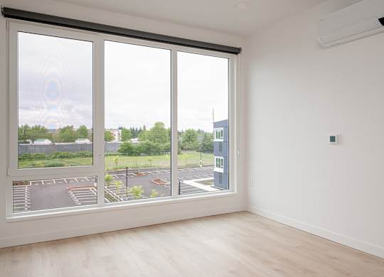 A room with a large window overlooking a parking lot.