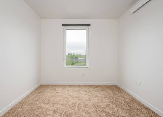 A room with a window and a view of trees outside.